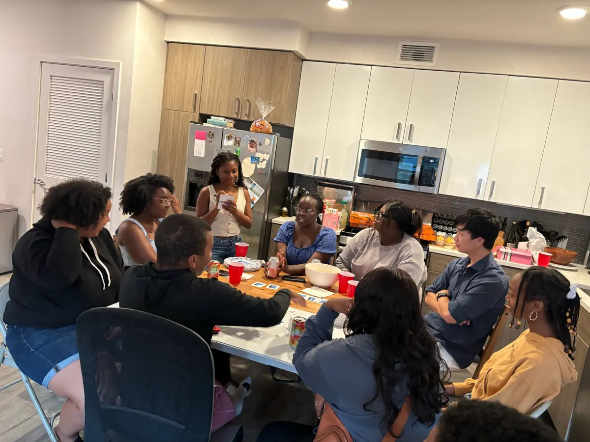 People share conversation around tables in a kitchen.